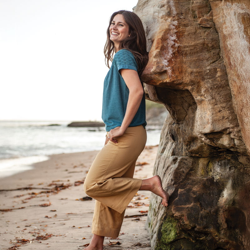 Woman leaning against rock overlooking ocean.