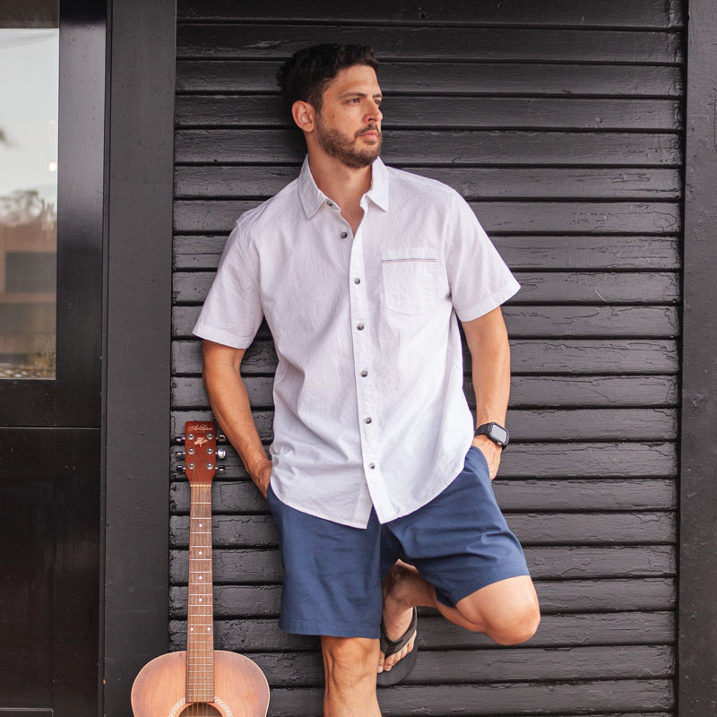 Man leaning against wall with guitar.